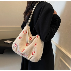 Detail of beige corduroy tote bag featuring red Future embroidery on a stylish model