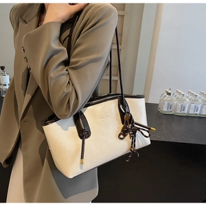 Detail of a beige tote bag with brown straps styled with a khaki blazer for work