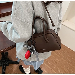 Detalle del bolso acolchado vintage marrón con colgante de corazón y llavero bola 8