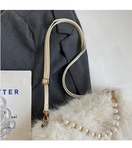 Detail of white faux fur handbag with elegant pearl handle and adjustable shoulder strap