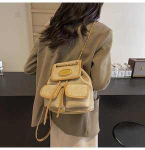 Détail d'un mini sac à dos en tweed kaki avec bordure en cuir et plaque dorée