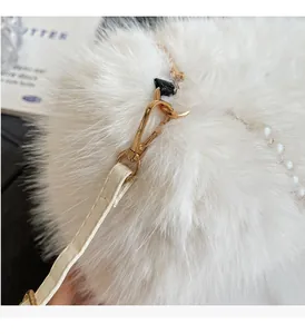 Close-up of white plush handbag featuring gold metal hardware and pearl strap details