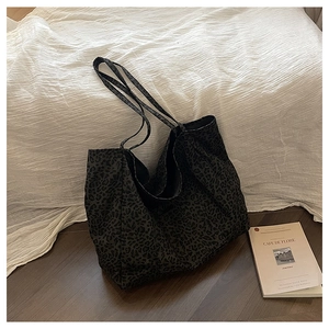 Detailed view of the large leopard print tote bag on a rustic wood floor backdrop