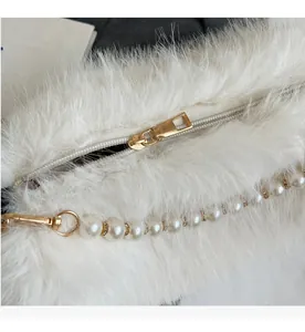 Close-up of white faux fur bag showing smooth golden zipper and elegant pearl strap details