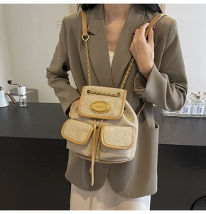 Détail d'un sac à dos en tweed avec bordures en cuir marron et bretelles en chaîne