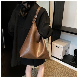 Close-up of deep brown tote bag with wrinkled leather texture and adjustable strap