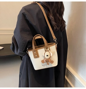 Detail der farblich abgesetzten Beuteltasche in Creme und Braun mit Affen-Anhänger