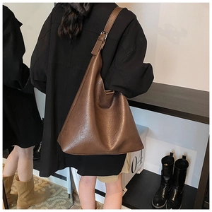Detail of adjustable wide shoulder strap on a brown leather-textured hobo tote bag