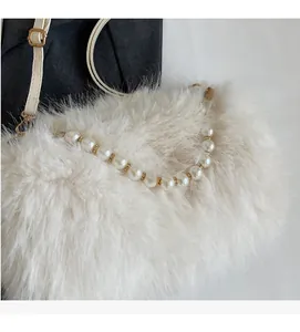 Detail view of cream faux fur bag with elegant pearl handle and gold metal clasp