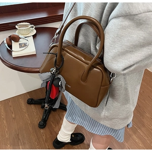 Primer plano de un bolso retro marrón con logo R♥K y lazo decorativo en un ambiente moderno