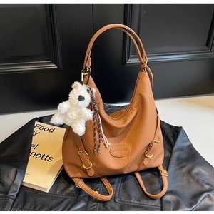 Close-up of brown pebbled leather crossbody bag with a cute white plush bear charm