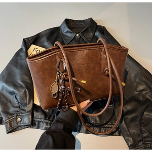 Detailed close-up of brown vintage tote bag with a unique tennis racket charm and metal pendant