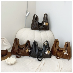 Close-up of vintage Hobo bags in four colors with baseball glove charms on a shelf