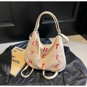 Detail of cream corduroy tote bag featuring red Our Future embroidery and leather straps