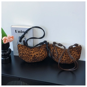 Detail of two leopard print crescent bags with knotted straps on a stylish black desk