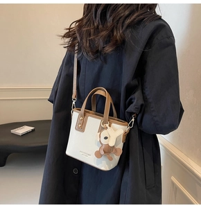 Modell mit zweifarbiger Mini-Tragetasche in Creme und Braun mit Tieranhänger-Detail