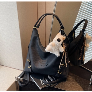 Close-up of black litchi grain leather bag with gold hardware and plush bear charm