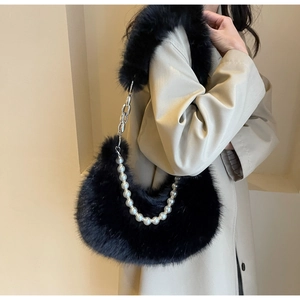 Détail du sac baguette noir en fausse fourrure avec bandoulière perle et chaîne sur modèle