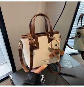 Detail der cremefarbenen Segeltuchtasche mit braunem Lederbesatz und Bärenanhänger