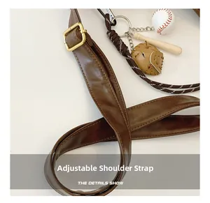Detail of adjustable dark brown leather shoulder strap with baseball charms and gold buckle