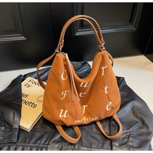 Close-up of brown corduroy tote bag with white embroidery on a leather jacket