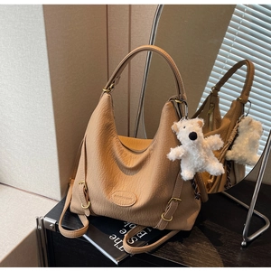 Detail of camel leather bag with lychee texture and cute white plush bear pendant