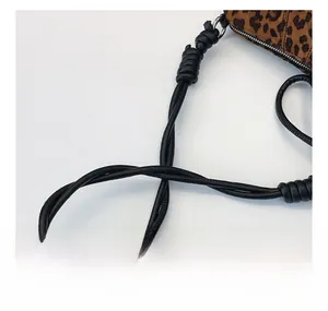 Detail of a black leather knotted shoulder strap on a leopard print hobo handbag