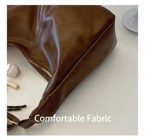 Detail showing smooth deep brown faux leather texture and gold-tone zipper of the bag