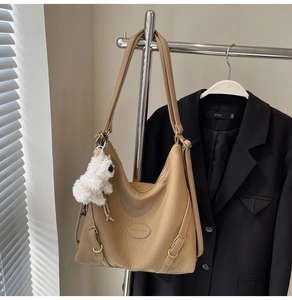 Detail of khaki leather hobo bag with lychee texture and cute plush puppy charm