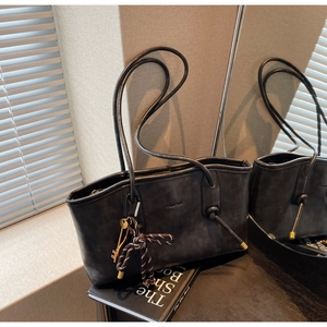 Detailed view of the dark matte leather tote bag with elegant key and tassel charms