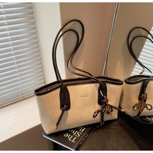 Detail of two-tone tote bag with rope handle and striped ribbon on books