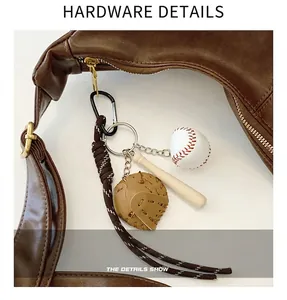 Detail of baseball glove, bat and ball keychain charm attached to a brown leather bag