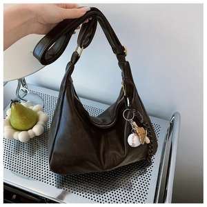 Detail of dark brown hobo bag featuring soft pleats and a creative baseball themed charm