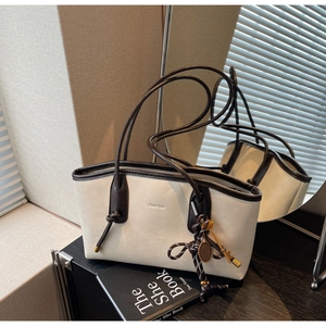 Detail of retro cream tote bag with brown leather trim and tennis racket charm