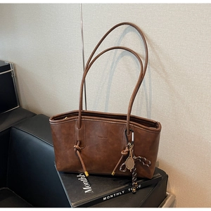 Detail of dark brown matte PU leather tote bag with decorative knot and tennis racket charm