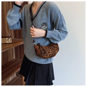 Detail of leopard print crescent bag with adjustable brown shoulder strap on model
