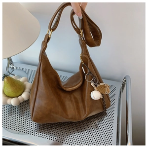 Macro view of brown hobo bag showing leather texture and baseball glove charm