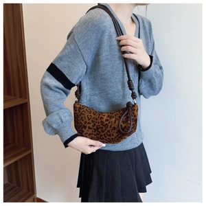 Close-up of leopard print crescent bag with brown leather knotted shoulder strap detail
