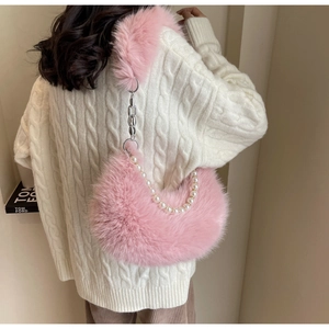 Sac hobo en fausse fourrure rose avec perles et chaîne porté sur un pull blanc
