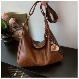 Detailed texture of brown PU leather hobo bag with wide strap and baseball pendant charm