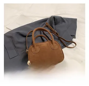 Vue de dessus d'un sac à main en daim marron avec bandoulière sur fond blanc et bleu