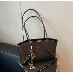 Detailed close-up of dark brown vintage tote bag with woven knot and gold key charms