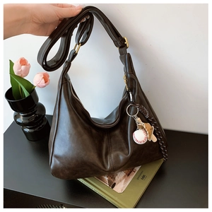 Detail of dark brown croissant bag with soft leather texture and baseball keychain charm