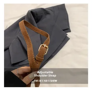 Détail de la bandoulière réglable en daim marron avec boucle en métal doré pour sac