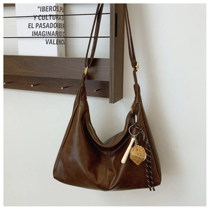 Detail of dark brown hobo bag with adjustable strap and creative baseball charm on hook