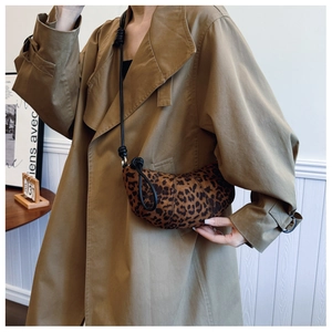 Detail of leopard print crescent bag with leather strap paired with a classic khaki trench coat