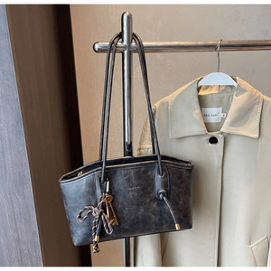 Detailed view of leather tote bag with vintage texture and metallic key charm hanging on strap