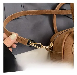 Vue macro du mousqueton doré et des coutures fines sur le sac à bandoulière marron