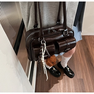 Détail du sac bandoulière marron brillant avec doubles poches à rabat et pendentif ourson