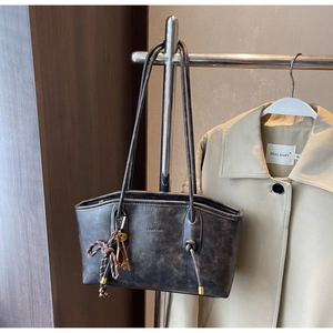 Detail of dark gray leather tote bag with woven rope decor and hanging key pendant